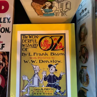 Collection of Wizard of Oz memorabilia, including a hardcover book with W.W. Denslow illustration, a package of themed bookmarks, and...