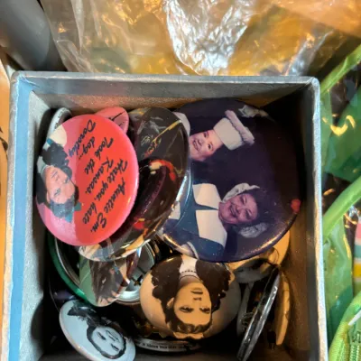 Collection of vintage Wizard of Oz pinback buttons inside a small blue storage box.