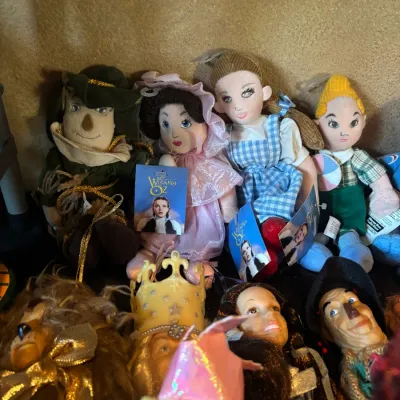 Collection of vintage Wizard of Oz plush dolls and figurines, including Dorothy, Glinda, Scarecrow, and the Cowardly Lion.