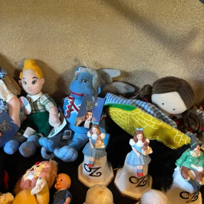 Sale Photo Thumbnail #101: Collection of vintage Wizard of Oz collectibles, including plush characters, small plastic dolls, and porcelain bell figurines.