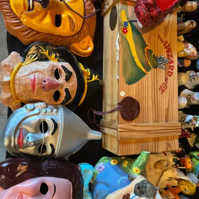 Sale Photo Thumbnail #119: Collection of The Wizard of Oz memorabilia including plastic character face masks, a wooden display crate with red sequin ruby slipper, and a Dorothy teapot.