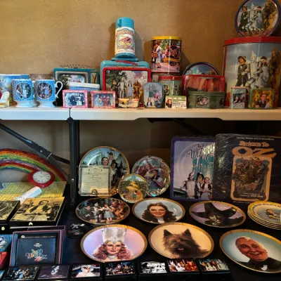 Collection of Wizard of Oz memorabilia, including vintage decorative plates, tins, lunchboxes, mugs, trading cards, and a vinyl...