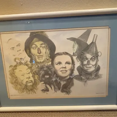 Framed illustration print featuring main characters from The Wizard of Oz, double-matted in blue and beige with a white frame.