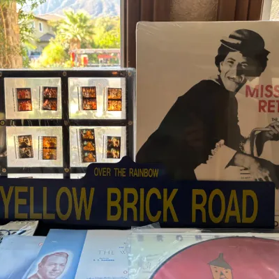 Collection of Wizard of Oz memorabilia, including a blue "Yellow Brick Road" street sign, framed film strips, and a "Miss...