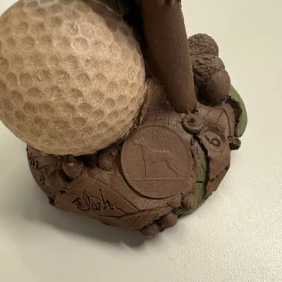 Tom Clark gnome figurine featuring a golf ball, acorns, and an embedded Irish coin, signed on the textured resin base.