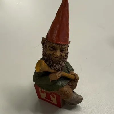 Vintage Tom Clark resin gnome figurine depicting a gnome with a red pointed hat seated on a letter block.