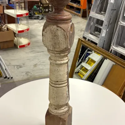 Antique carved wooden newel post with a spherical finial and weathered, crackled white paint over a dark wood core.