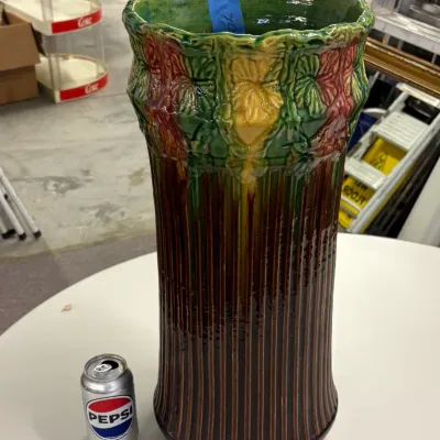 Large Art Nouveau style ceramic umbrella stand featuring raised floral motifs and a ribbed body in a polychrome glaze.