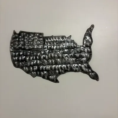 Handcrafted metal wall art shaped like the contiguous United States, featuring an embossed American flag pattern and floral accents.