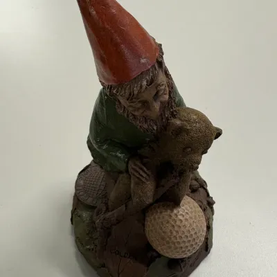 Tom Clark gnome figurine by Cairn Studio, depicting a gnome holding a teddy bear near a golf ball on a naturalistic base.