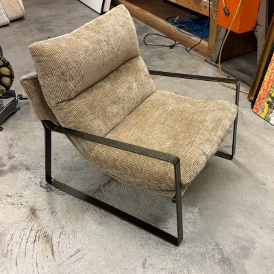 Modernist arm chair with textured beige corduroy-style upholstery and a dark textured metal frame.