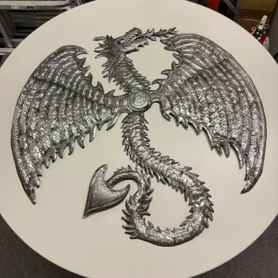 Handcrafted Haitian oil drum metal art sculpture depicting a dragon with spread wings and textured detailing.
