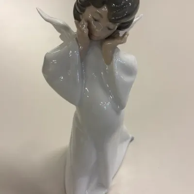 Lladro glazed porcelain figurine depicting a thoughtful angel with hands under her chin.