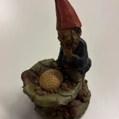 Vintage Tom Clark resin gnome figurine featuring a gnome examining a golf ball on a bed of leaves, in good condition.