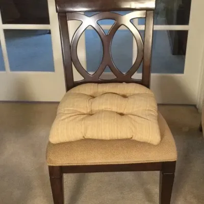 Contemporary dark wood dining chair featuring an overlapping oval motif backrest, textured beige upholstered seat, and an additional...