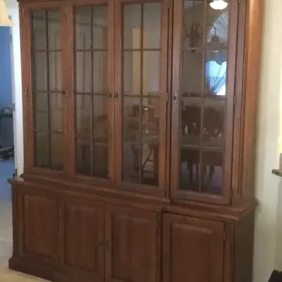 Large wooden two-piece hutch featuring glass-paneled display cabinets above lower solid wood storage doors with detailed crown molding.