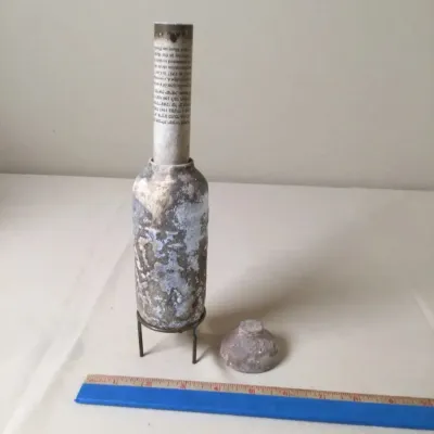 Vintage ceramic or stone Mezuzah case with a printed scroll insert, detachable top piece, and small wire stand.