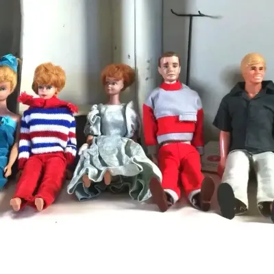 Collection of five vintage fashion dolls from the 1960s to 1970s, including Barbie, Ken, and Midge figures dressed in original period...