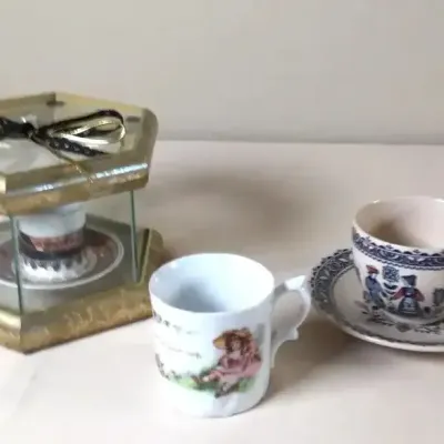 Collection of decorative miniature teacups and mugs, including a blue-and-white teacup with matching saucer, a child-themed mug, and a...
