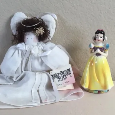 Handmade fabric angel doll with a 'Twice Is Nice' tag alongside a ceramic Snow White porcelain figurine.