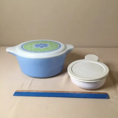 Vintage Pyrex casserole dish in the Horizon Blue medallion pattern alongside a small Corning Ware saucemaker, accompanied by a wooden...