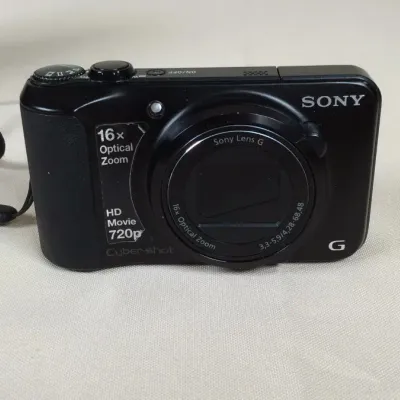 Black Sony Cyber-shot digital camera with a 16x optical zoom Sony Lens G and attached wrist strap, circa 2010s.