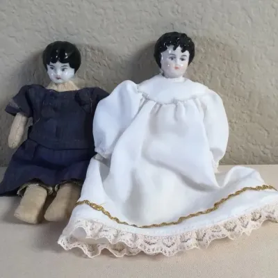 Pair of antique china head dolls with cloth bodies and molded black hair, dressed in custom fabric gowns.