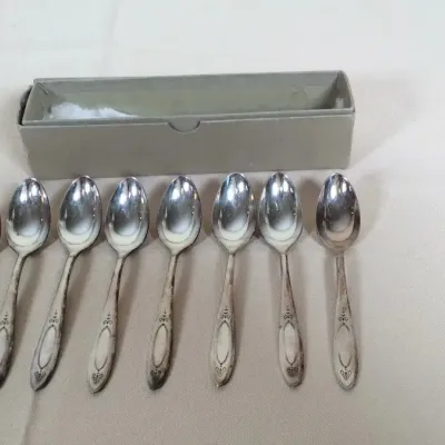 Set of eight vintage silver-plated demitasse spoons with subtle tarnish, complete with original storage box.