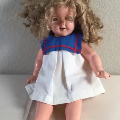 Vintage Shirley Temple composition doll, circa 1930s, featuring curly blonde hair and wearing a sailor-style dress.