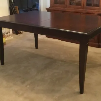Dark wood extendable dining table with tapered square legs and a polished top.