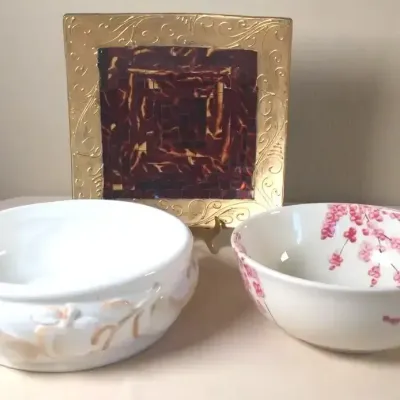 Two decorative ceramic bowls paired with a square mosaic display plate featuring a gilded relief border and tortoise-shell style center.