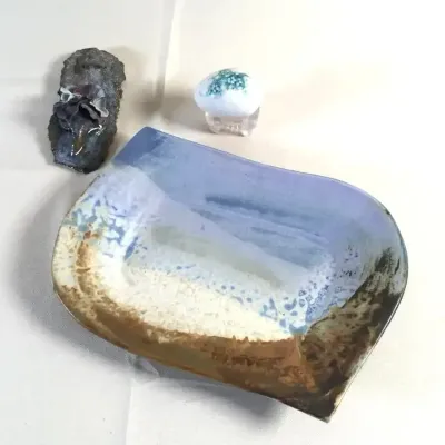 Studio pottery glaze-catch dish, accompanied by a small mineral specimen cluster and a glass paperweight egg with stand.