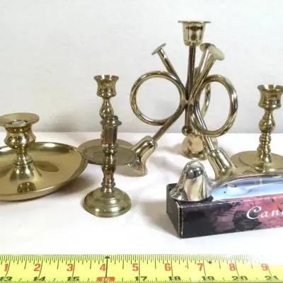 Assortment of polished brass candlesticks, including a chamberstick, a French horn design, and a boxed silver-tone candle snuffer.