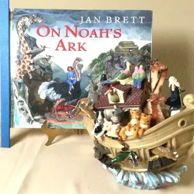Copy of Jan Brett's children's book "On Noah's Ark" paired with a detailed resin Noah's Ark figurine set on...