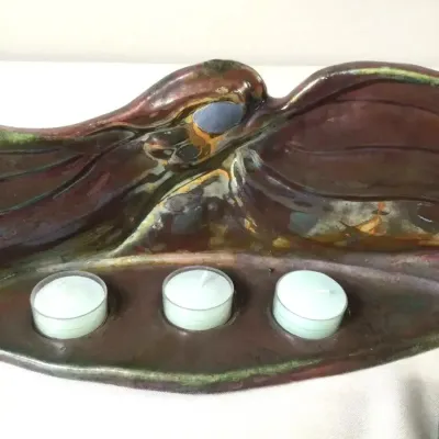 Organic modern studio pottery tealight candle holder with iridescent metallic glaze.