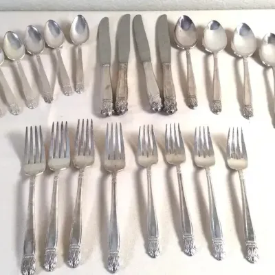 Vintage silver-plated flatware set featuring stylized handles, including knives, forks, soup spoons, and teaspaoons.