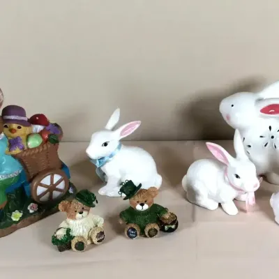 Collection of decorative Easter figurines, featuring ceramic and resin rabbits, a rabbit riding a tricycle with a cart, and two small...