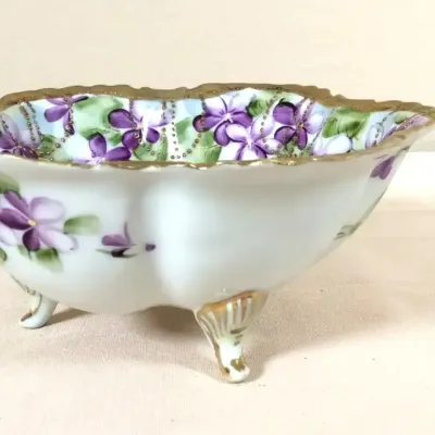 Antique hand-painted porcelain footed bowl featuring purple violet motifs and gilded trim.