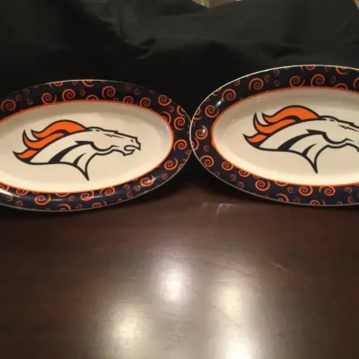 Pair of Denver Broncos ceramic oval serving platters featuring the team logo and a swirled navy and orange border design.