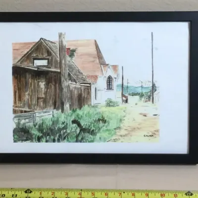 Framed watercolor landscape painting featuring a rural scene with wooden structures and a church, signed "CALDER" in the lower...