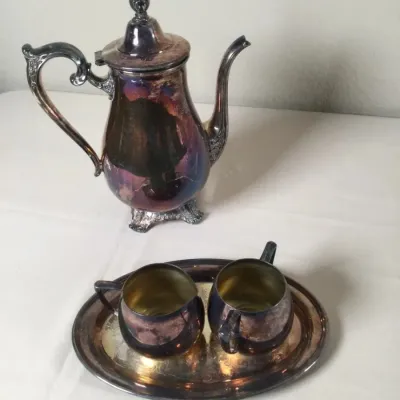 Four-piece silver-plated tea set including a tall coffee or teapot, creamer, sugar bowl, and matching oval tray, all displaying heavy...