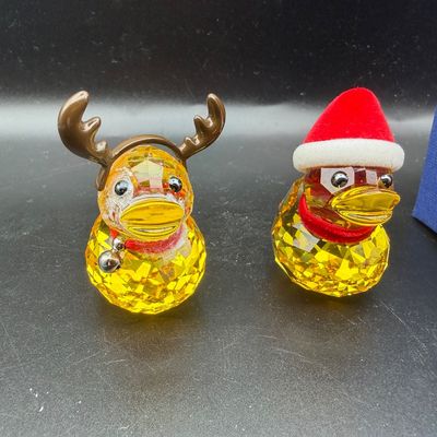 Sale Photo Thumbnail #5: Pair of Swarovski-style yellow crystal duck figurines with festive holiday accessories, including reindeer antlers and a Santa hat.
