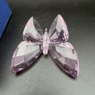 Sale Photo Thumbnail #38: Swarovski crystal light pink butterfly figurine with faceted wings, shown next to its original blue box.