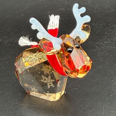 Sale Photo Thumbnail #11: Swarovski crystal Mo reindeer figurine featuring light topaz crystal body with snowflake etching, clear crystal antlers, and a red fabric scarf.