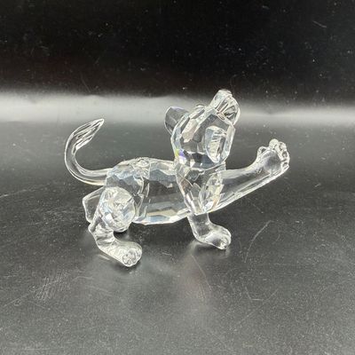 Sale Photo Thumbnail #32: Swarovski crystal lion cub figurine depicted in a playful pose with one paw raised.