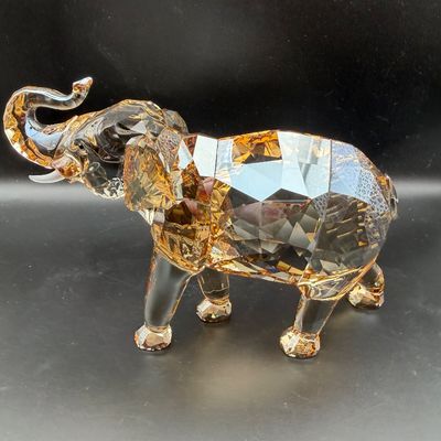 Sale Photo Thumbnail #43: Swarovski Faceted crystal elephant figurine in golden amber and clear glass tones with trunk raised.