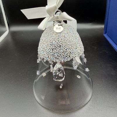 Sale Photo Thumbnail #10: Swarovski crystal bell ornament featuring a clear glass body encrusted with sparkling pave crystal accents and hanging from a white satin ribbon.