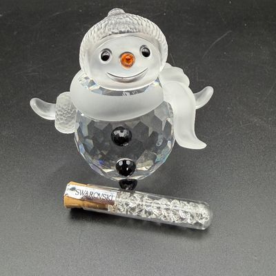 Sale Photo Thumbnail #18: Swarovski crystal snowman figurine featuring frosted glass details and a faceted body, accompanied by a branded glass vial of loose crystals.