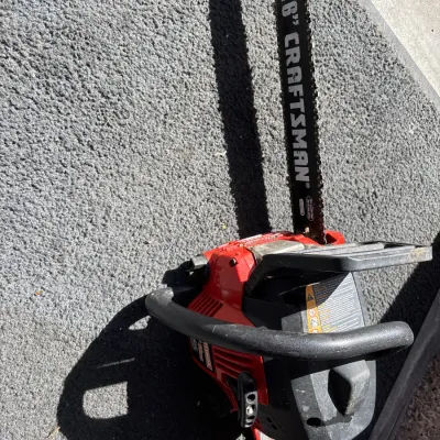 Craftsman gas-powered chainsaw featuring a 16-inch guide bar and a red and black composite body, showing light cosmetic wear.