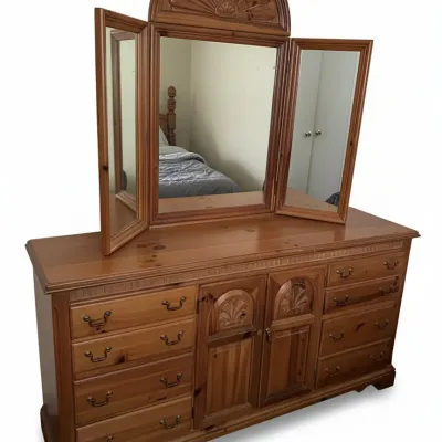 Rustic knotty pine dresser with a central tri-fold mirror featuring carved shell details and matching wooden hardware.